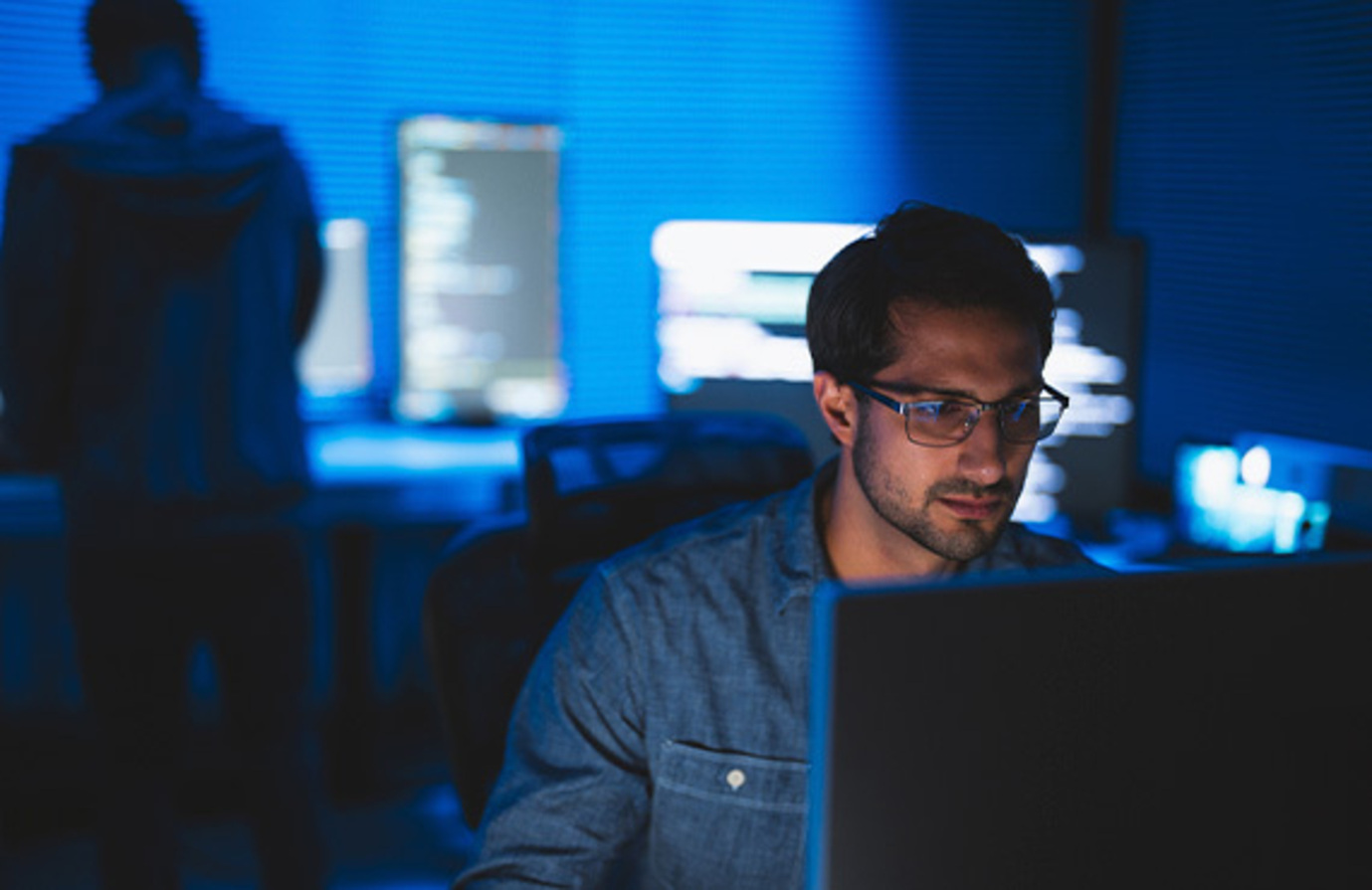 A worker in a control room monitoring cybersecurity for industrial process control systems.