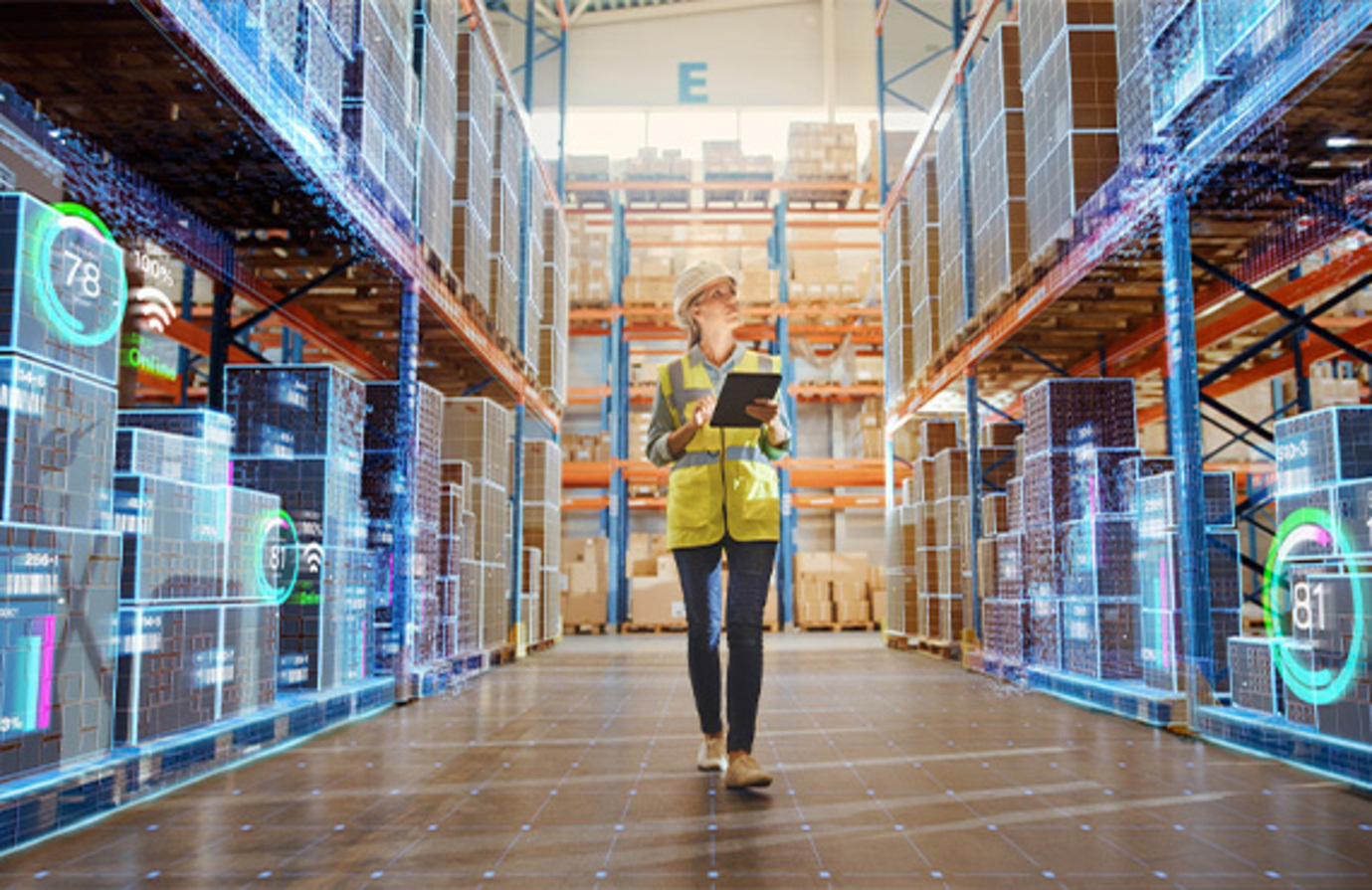 Woman in a warehouse using a digital tablet for IIoT asset management, surrounded by shelves and equipment.