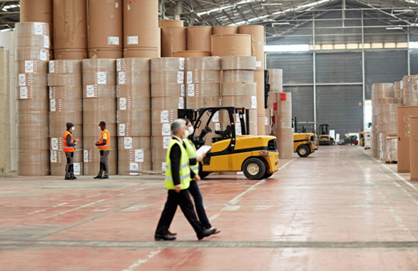Workers in warehouse monitoring machine conditions in paper manufacturing industry.