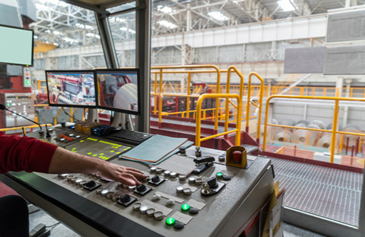 A man in a shipyard control room overseeing secure industrial controls.