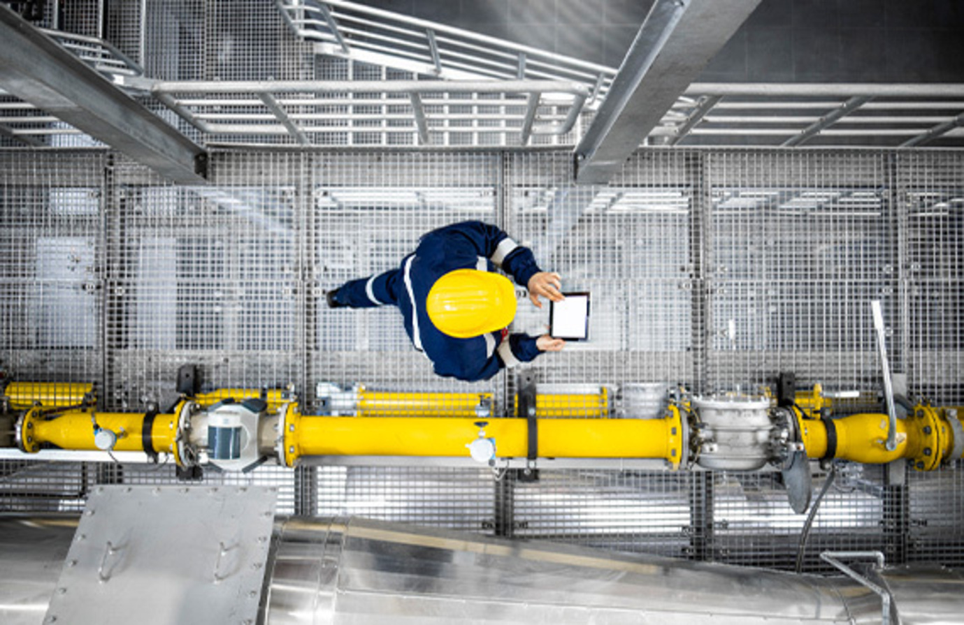 An engineer examines a factory pipe, highlighting the importance of safety in offshore oil and gas platforms with advanced process control.