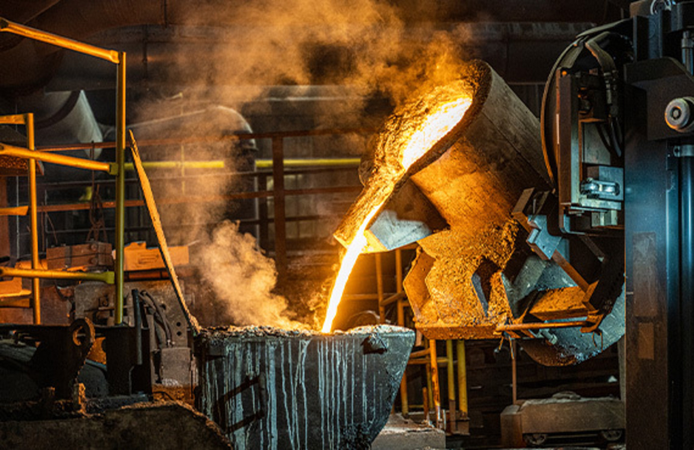 A metals industry casting machine pouring molten metal into a pot.