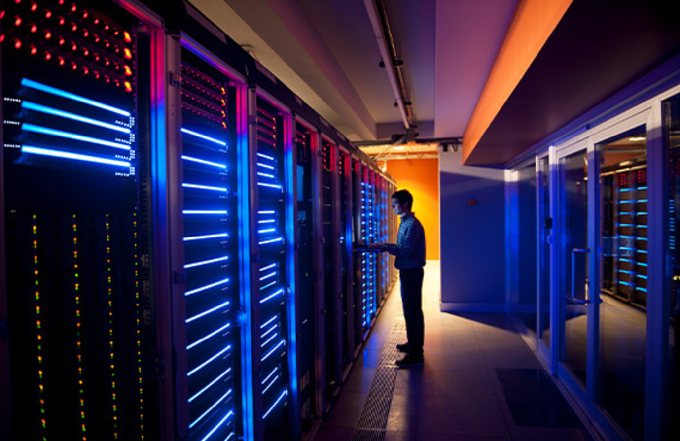 A man stands in a data center with blue lights, ensuring industrial network security.