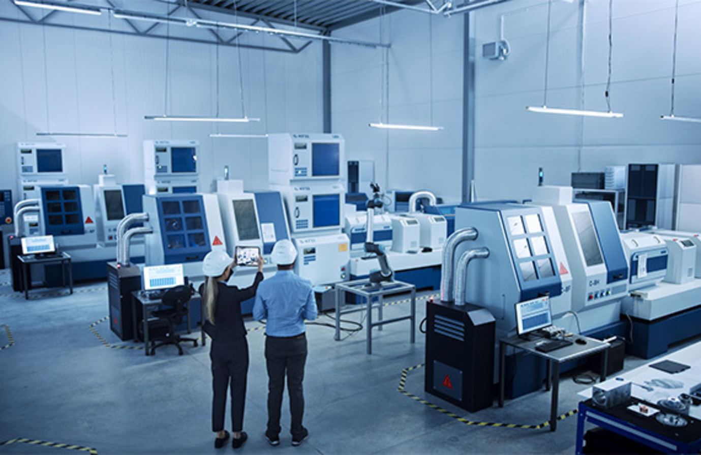 Two individuals standing in front of a large machine, strategizing for a manufacturing cybersecurity roadmap