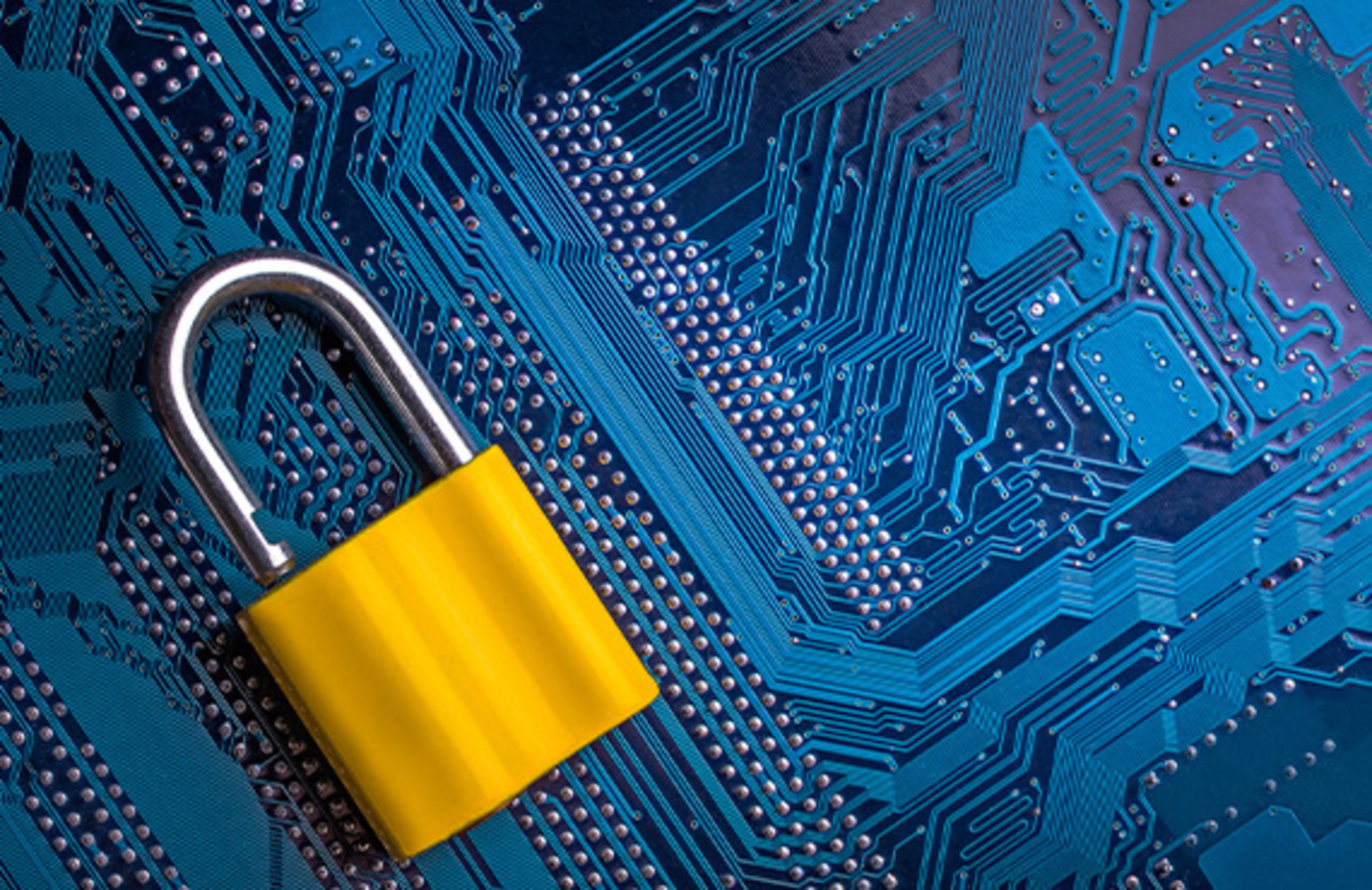 A yellow padlock on a circuit board highlights the critical role of cybersecurity in the manufacturing sector.