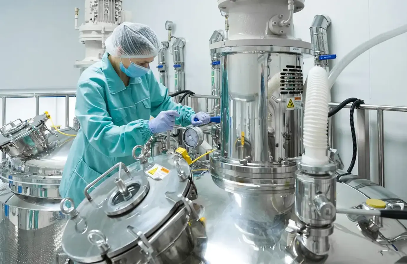 Pharmaceutical technician operating a sanitary diaphragm valve on a bioreactor