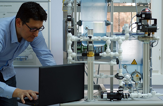 A man working on Pid controllers using a laptop in a laboratory.