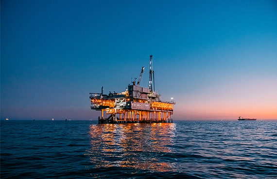 An oil rig silhouetted against a dusky ocean backdrop, emphasizing the need for advanced safety in offshore platforms.