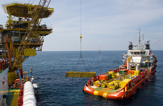 Large materials are lifted by a crane over the ocean, showcasing advanced safety measures in offshore operations