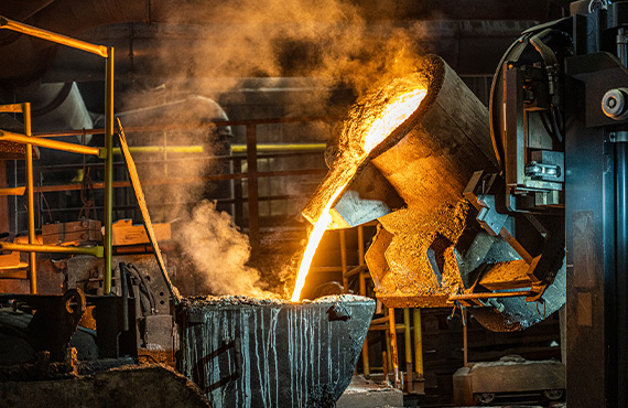 A metals industry casting machine pouring molten metal into a pot.