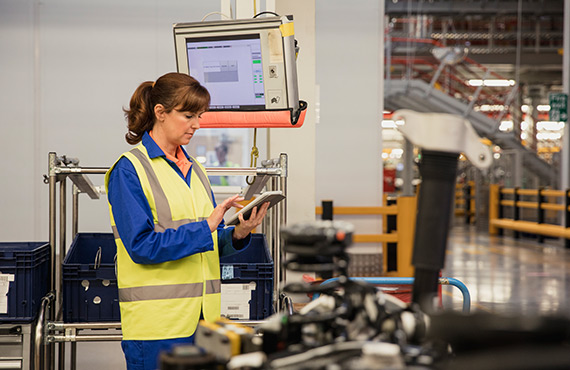 A team member in a factory using a tablet for automated process control system programming.