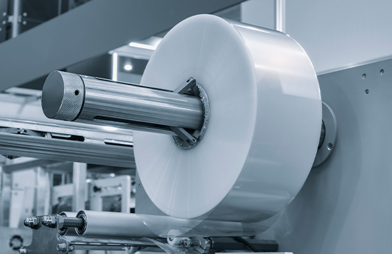 A machine in the pulp and paper industry, featuring a large roll of paper stock ready for processing.