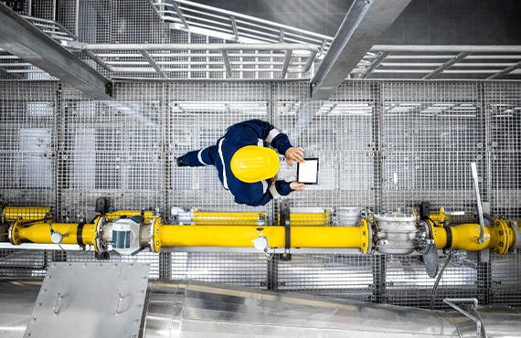 An engineer examines a factory pipe, highlighting the importance of safety in offshore oil and gas platforms with advanced process control.