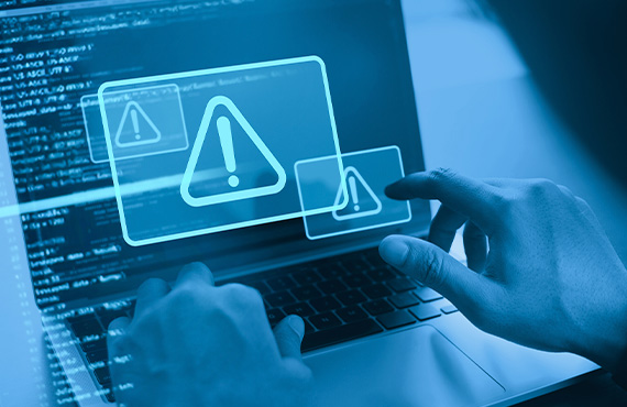 Hands over a laptop experiencing a cyber attack, addressing cyber risks in Industrial Control Systems.