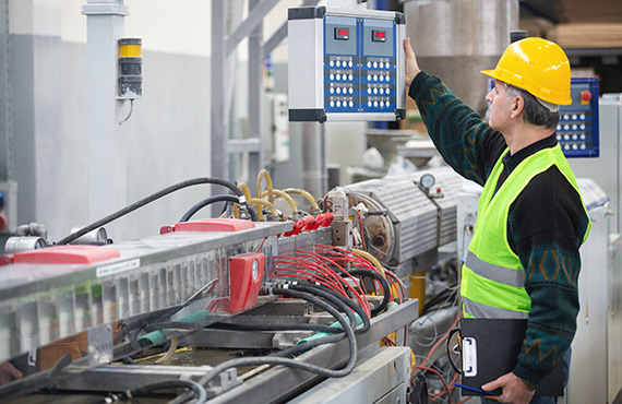 An employee in a factory, troubleshooting an automated process control system.