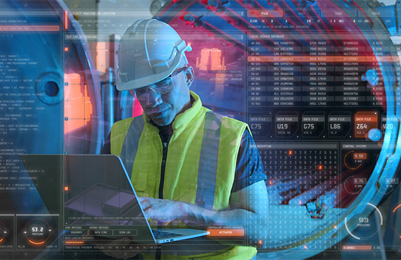 A man wearing a hard hat and safety vest, working on a laptop to enhance cybersecurity in the manufacturing sector.