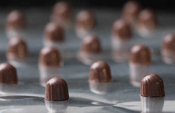 Batch processing of delicious chocolate candies on a production line, showcasing the meticulous craftsmanship and quality control.