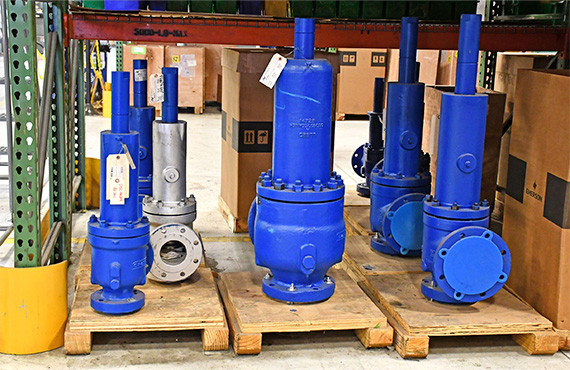 A variety of blue Crosby Pressure Relief Valves on pallets in a valve repair facility