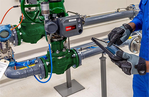 Worker on a tablet next to a set of Fisher control valves