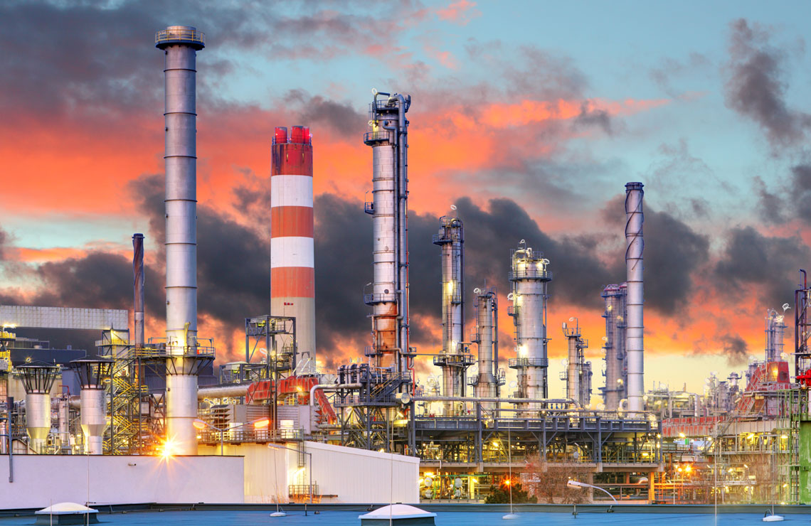 Oil refinery with distillation towers at sunset