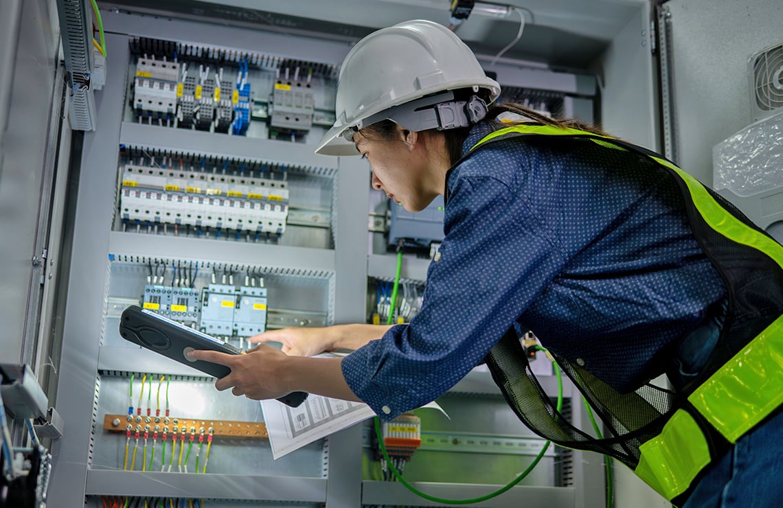 Systems engineer inspecting PLCs in a cabinet